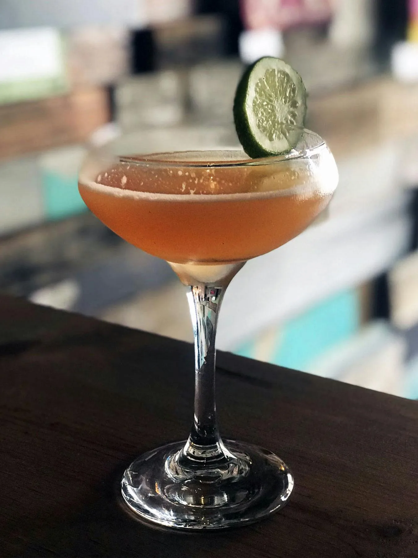Cocktail in a coupe glass with a lime wheel