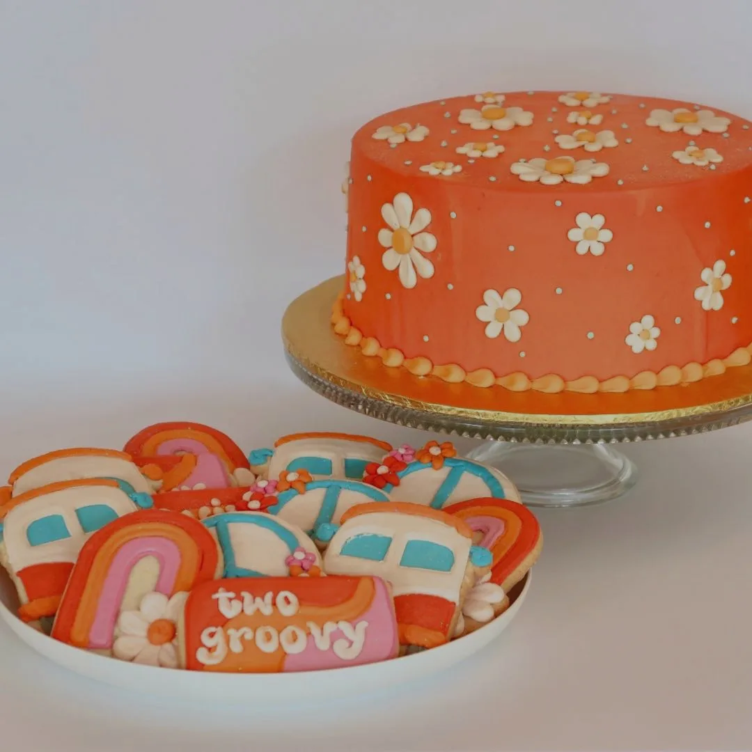 Decorated orange cake with flower designs and iced cookies