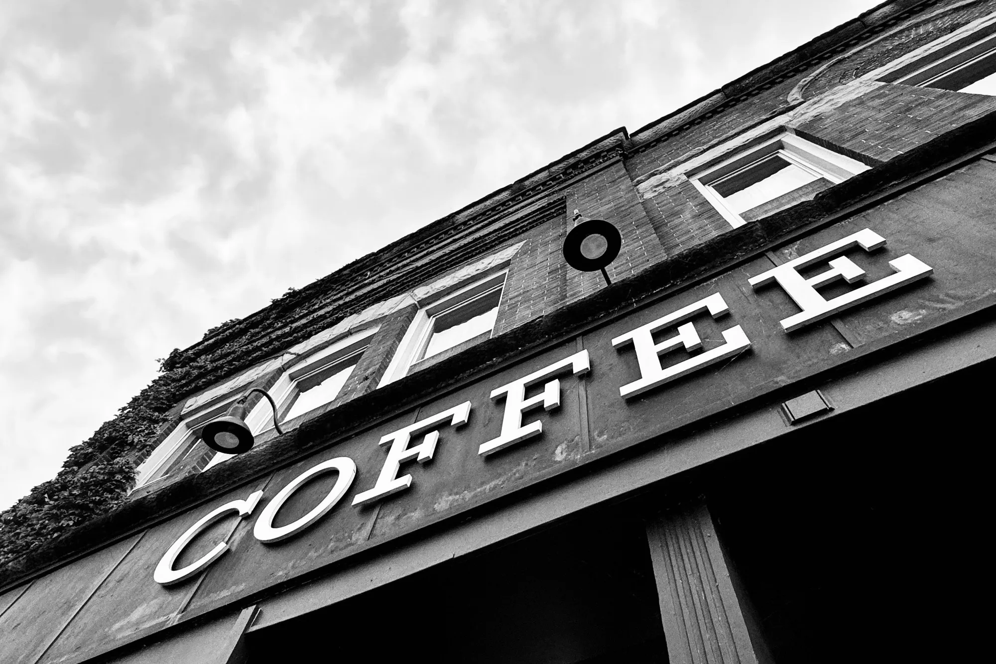 Black-and-white view of a Coffee sign on a building facade